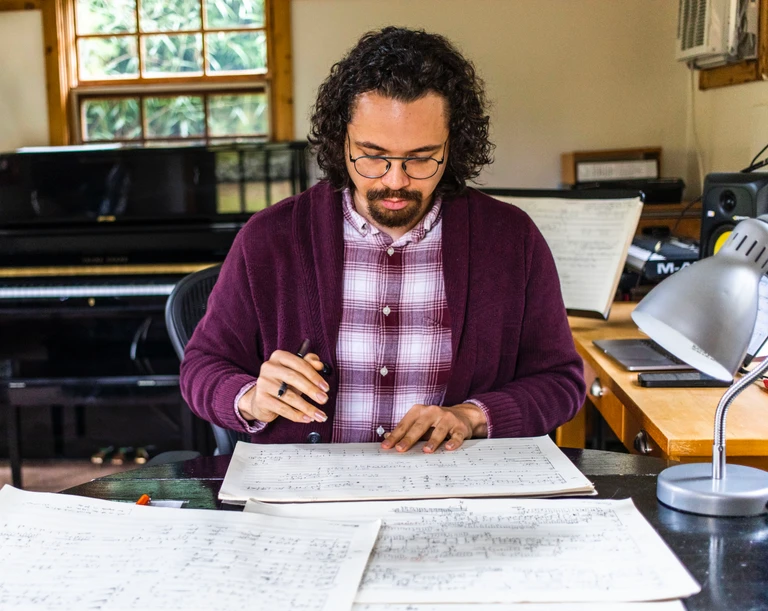 Black and white portrait of Tyler Taylor, late 20s, long dark hair, goatee, aviator sunglasses wearing a black vneck shirt.